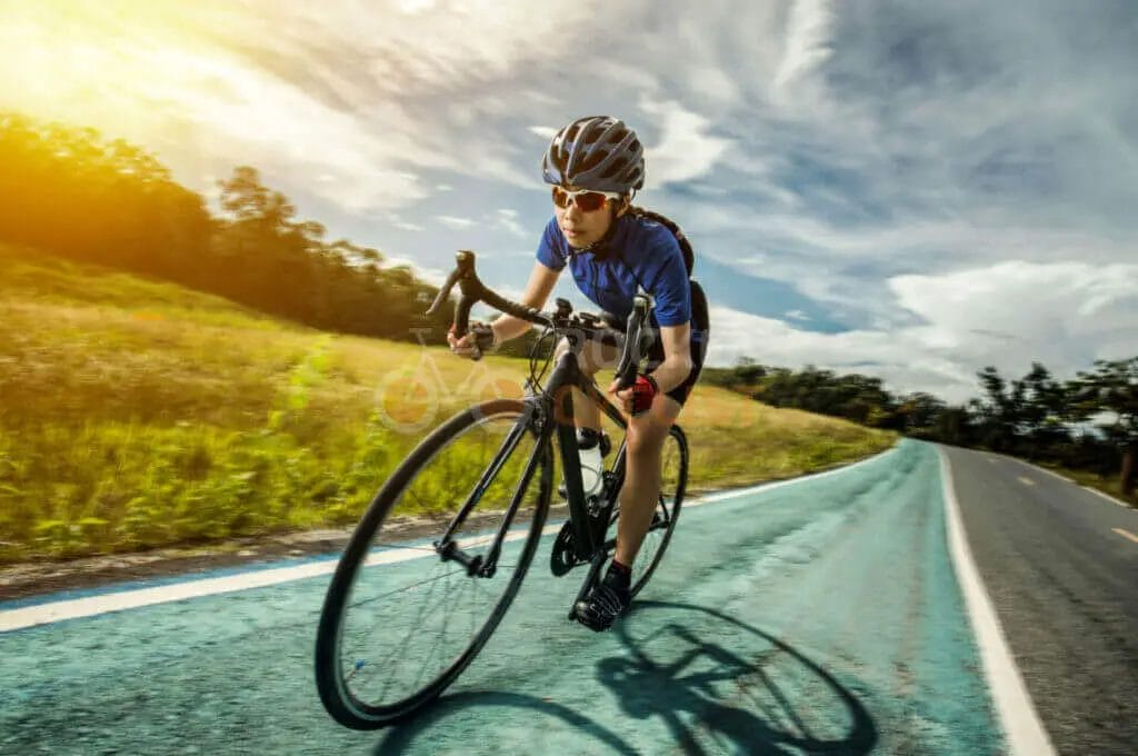 Cyclist in action on a sunny day with clouds in the background.