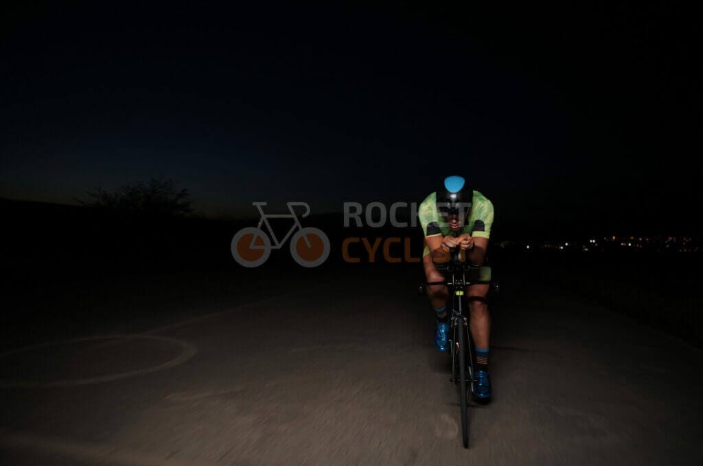 A cyclist riding down a road at night.