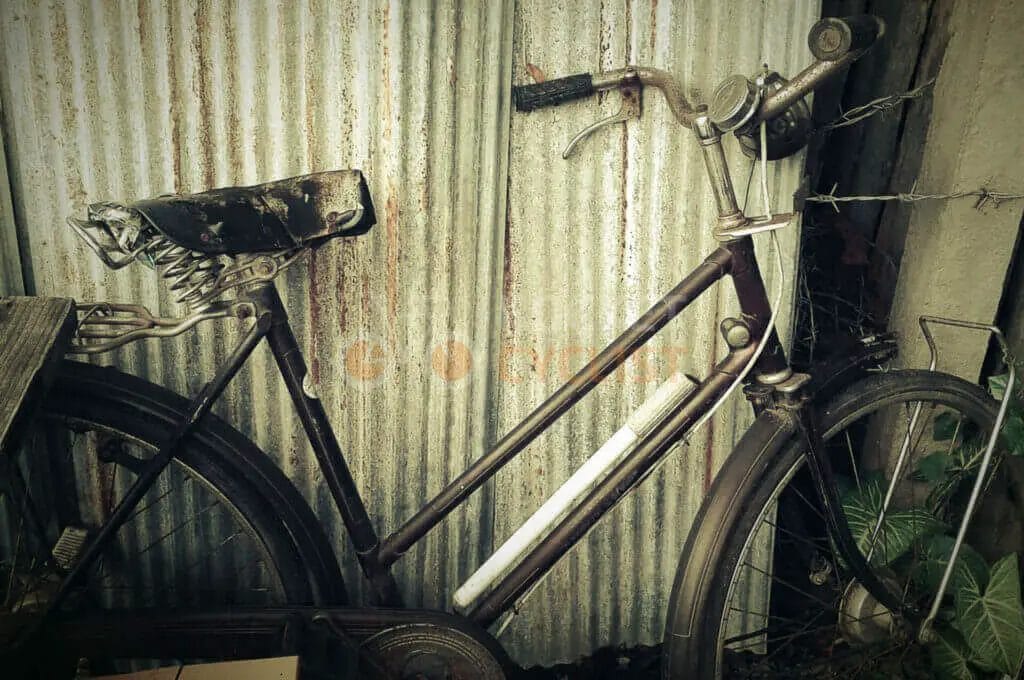 A bicycle leaning against a corrugated metal wall.