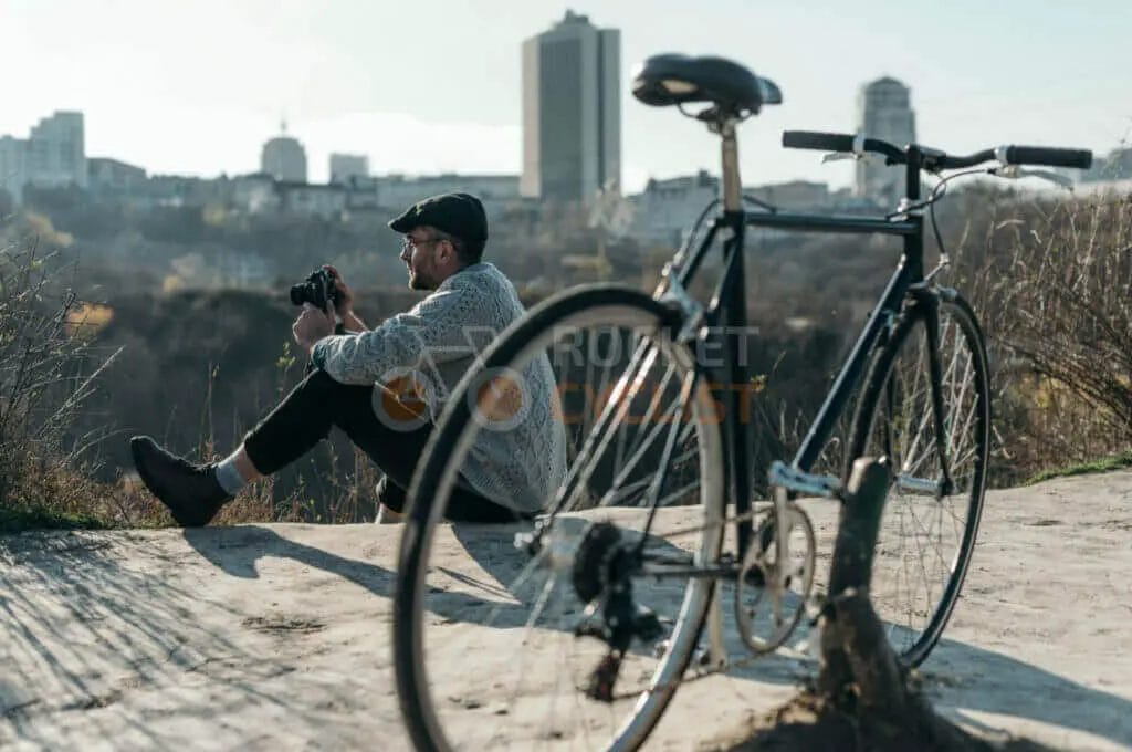 A man sitting on a bench with a bicycle in front of him.