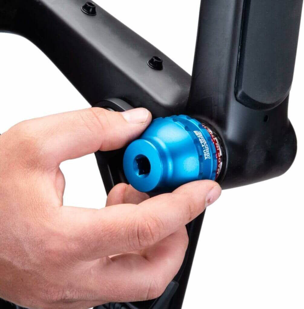 A person is putting a blue knob on a bike frame.