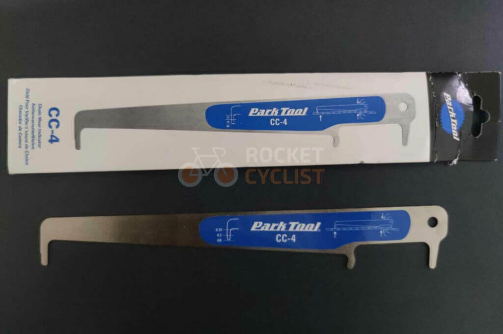 Two Park Tools CC-4 chain wear indicators, one in packaging and one out, displayed on a dark surface. These durable tools, made in the USA, are essential for measuring chain wear on bicycles.