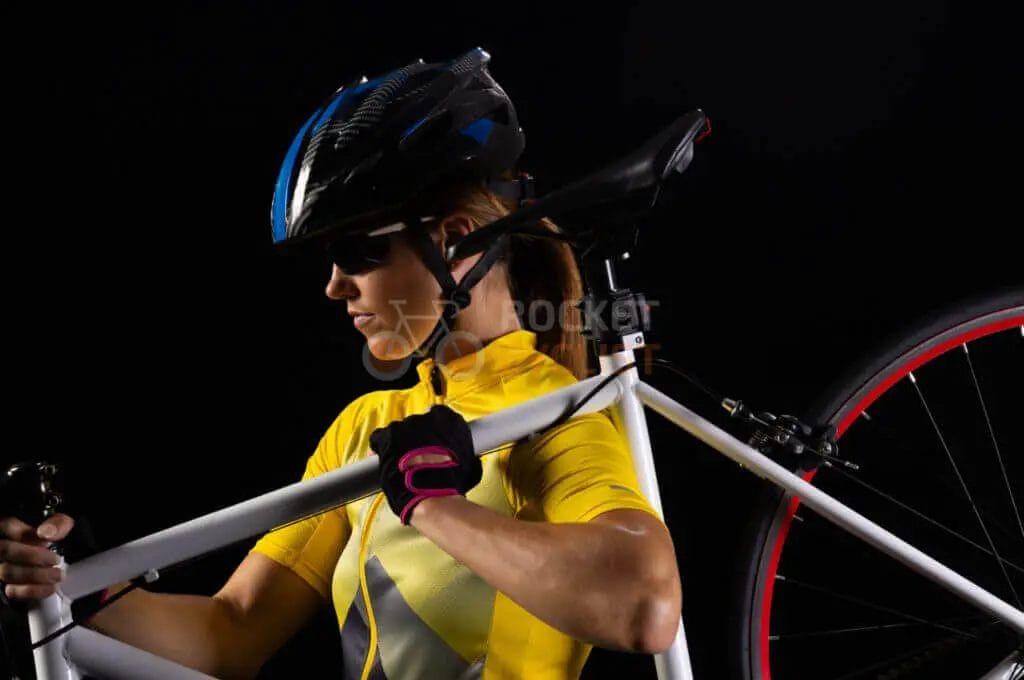 A woman is posing with her bike on a black background.