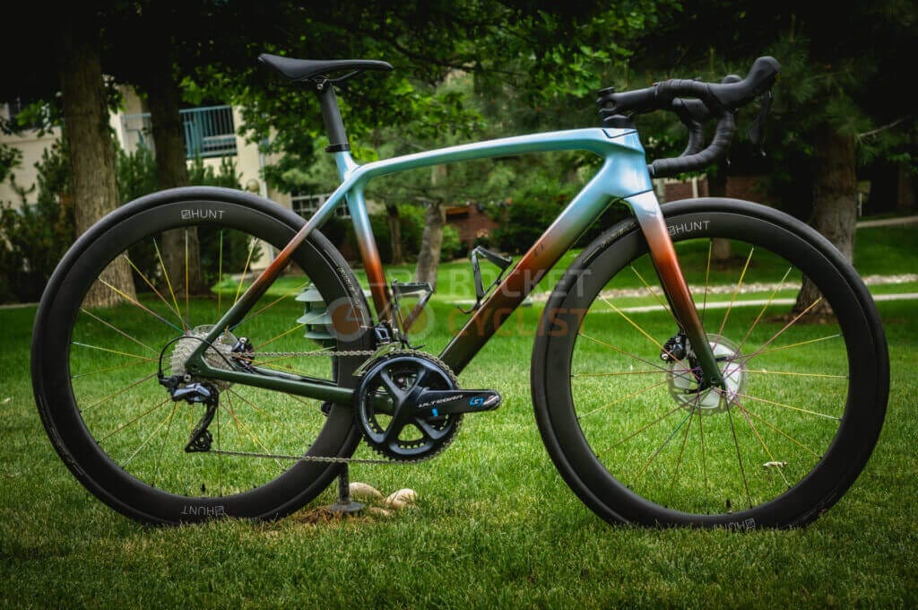 A bike is parked on the grass in front of a park.