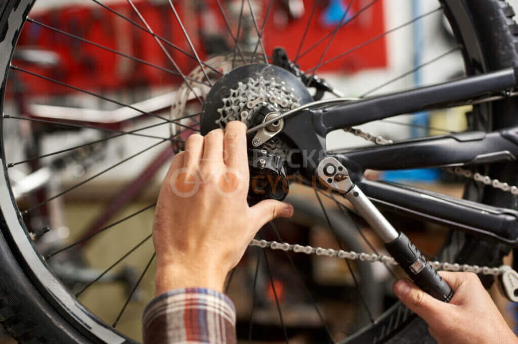A man fixing a bicycle wheel in a workshop.