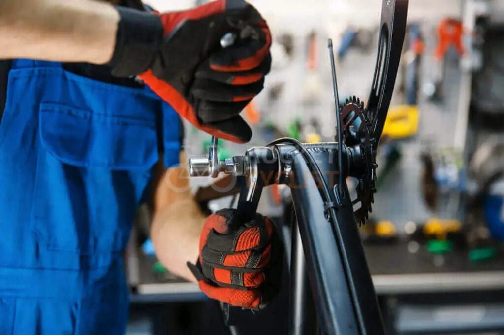 A person in gloves fixing a bicycle.