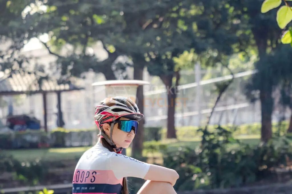 A woman wearing a helmet and sunglasses sitting on a bicycle.