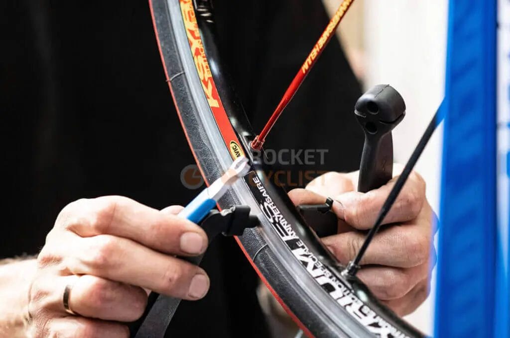 A person using a tool to fix a bicycle tire.